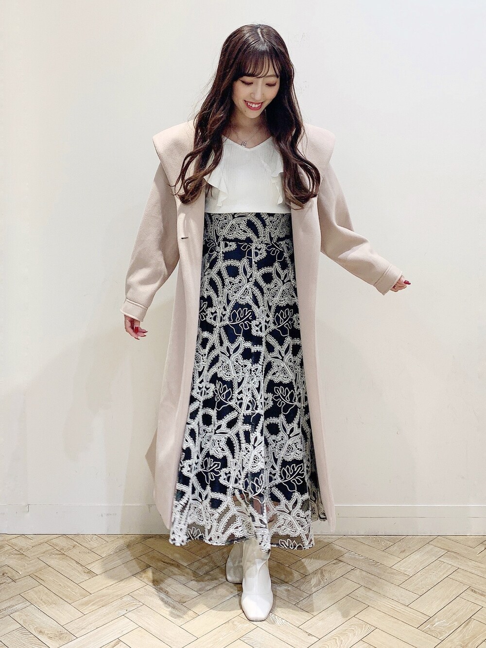 ブラック系のスカート、ホワイト系のニット/セーター、ベージュ系のチェスターコートを着用したレディースの冬コーディネートの7枚目の写真