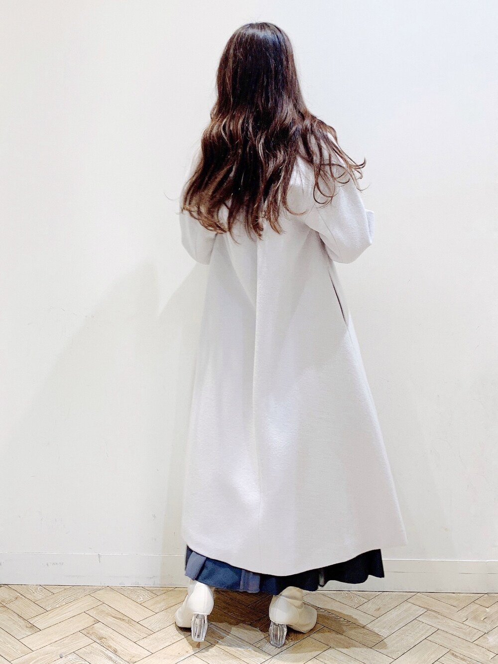 グレー系のニット/セーター、グレー系のスカート、ホワイト系のブーツを着用したレディースの冬コーディネートの9枚目の写真