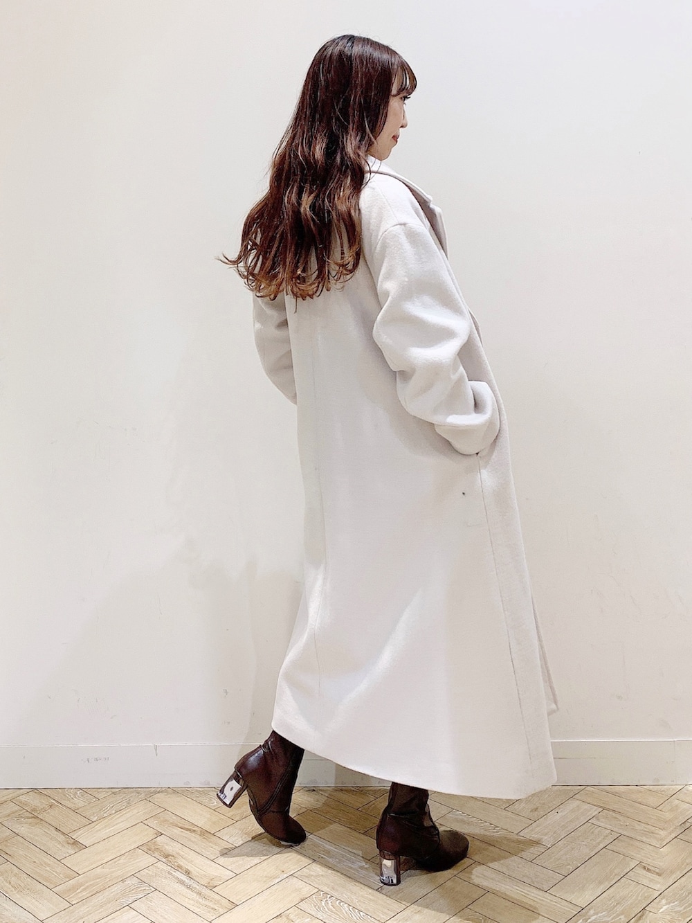 ベージュ系のワンピース、ホワイト系のチェスターコート、ブラウン系のブーツを着用したレディースの冬コーディネートの8枚目の写真