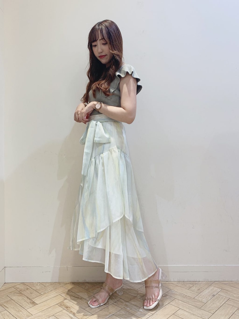 グリーン系のスカート、ベージュ系のサンダル、グリーン系のニット/セーターを着用したレディースの春コーディネートの4枚目の写真