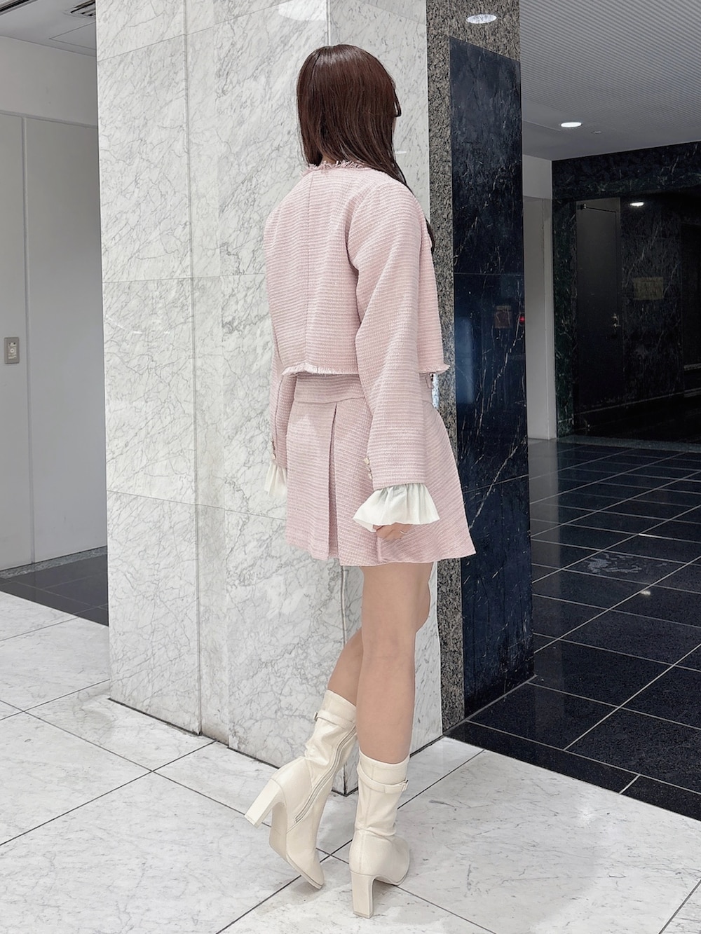 ピンク系のノーカラージャケット、ピンク系のスカート、ホワイト系のブーツを着用したレディースの冬コーディネートの4枚目の写真