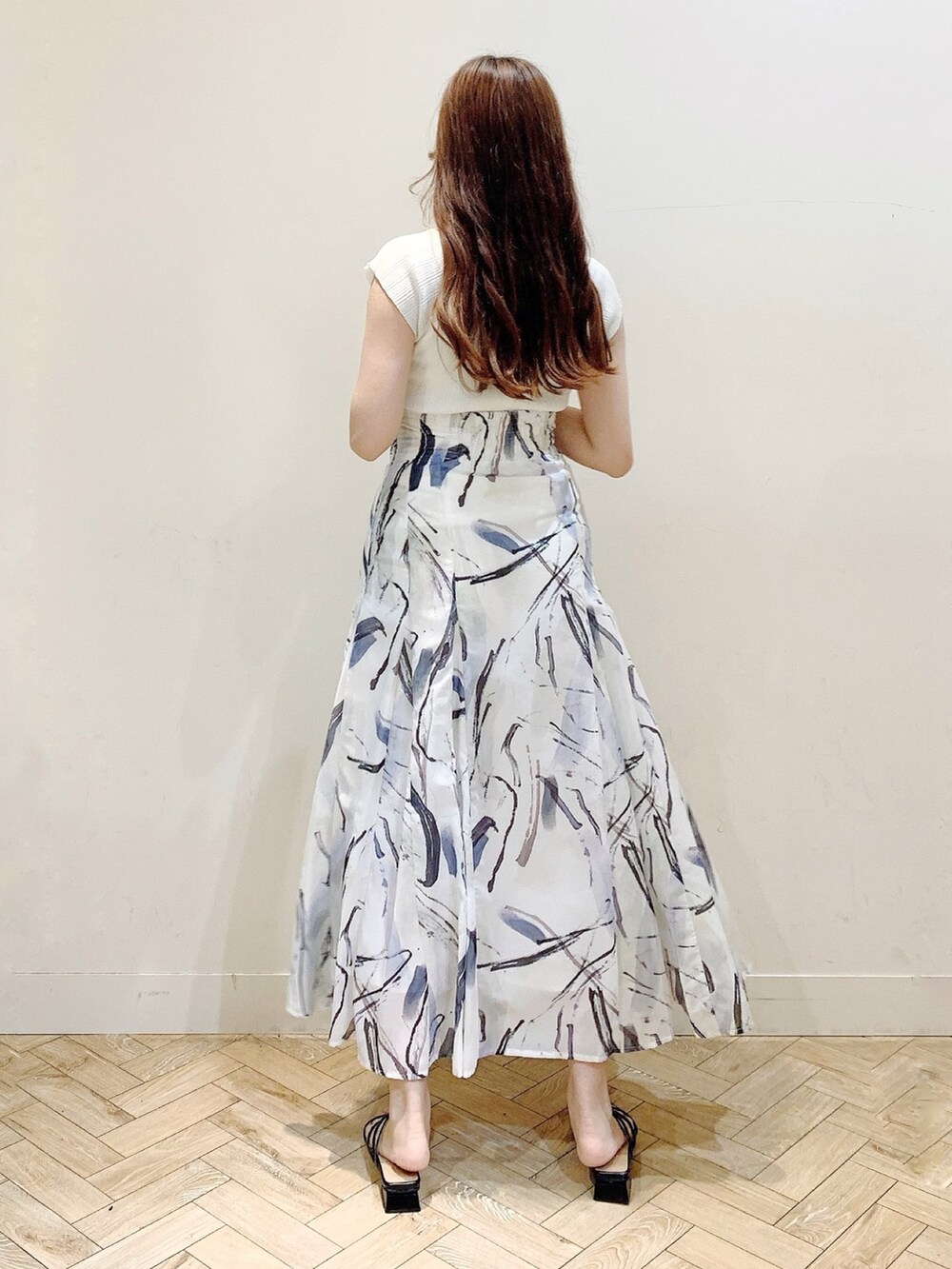 ホワイト系のニット/セーター、グレー系のスカート、ブラック系のサンダルを着用したレディースの夏コーディネートの6枚目の写真