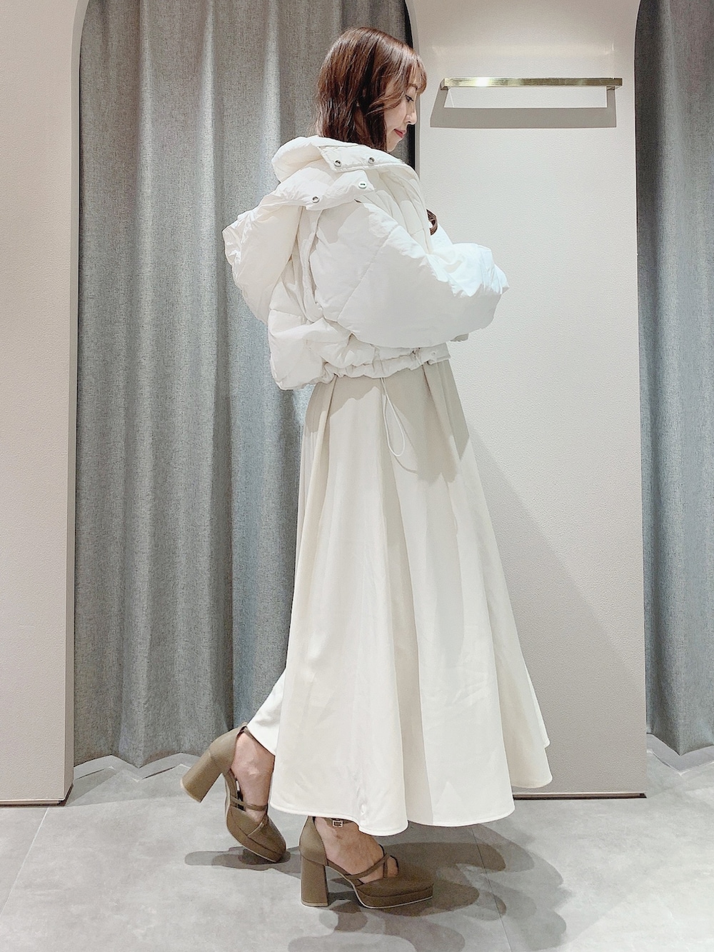 ベージュ系のパンプス、ホワイト系のワンピース、ホワイト系のダウンジャケット/コートを着用したレディースの秋コーディネートの4枚目の写真