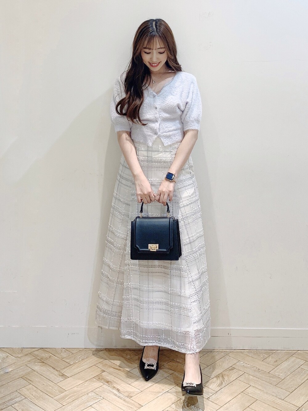 パープル系のカーディガン/ボレロ、ブラック系のスカート、ブラック系のパンプスを着用したレディースの夏コーディネートの3枚目の写真