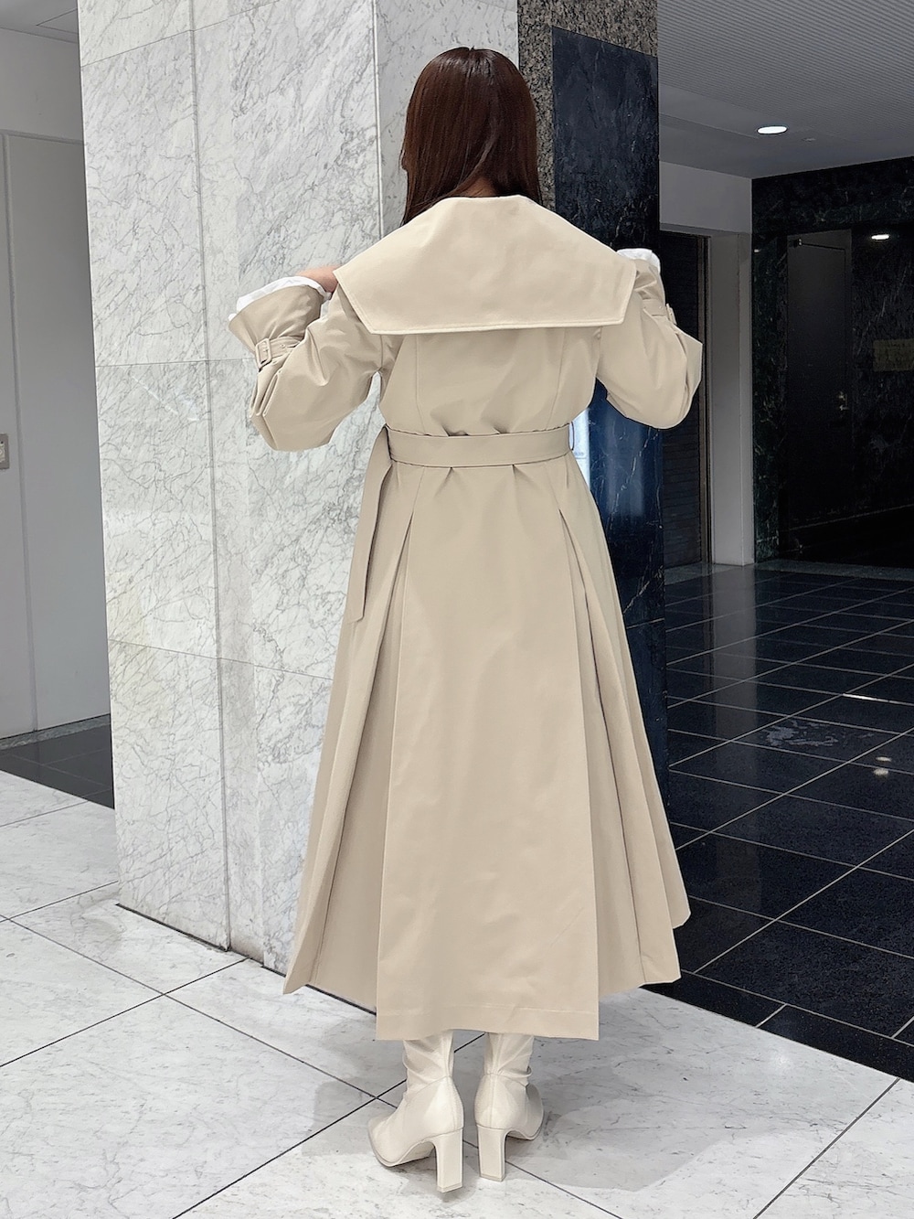 ホワイト系のブーツ、ベージュ系のトレンチコート、ホワイト系のワンピースを着用したレディースの冬コーディネートの5枚目の写真