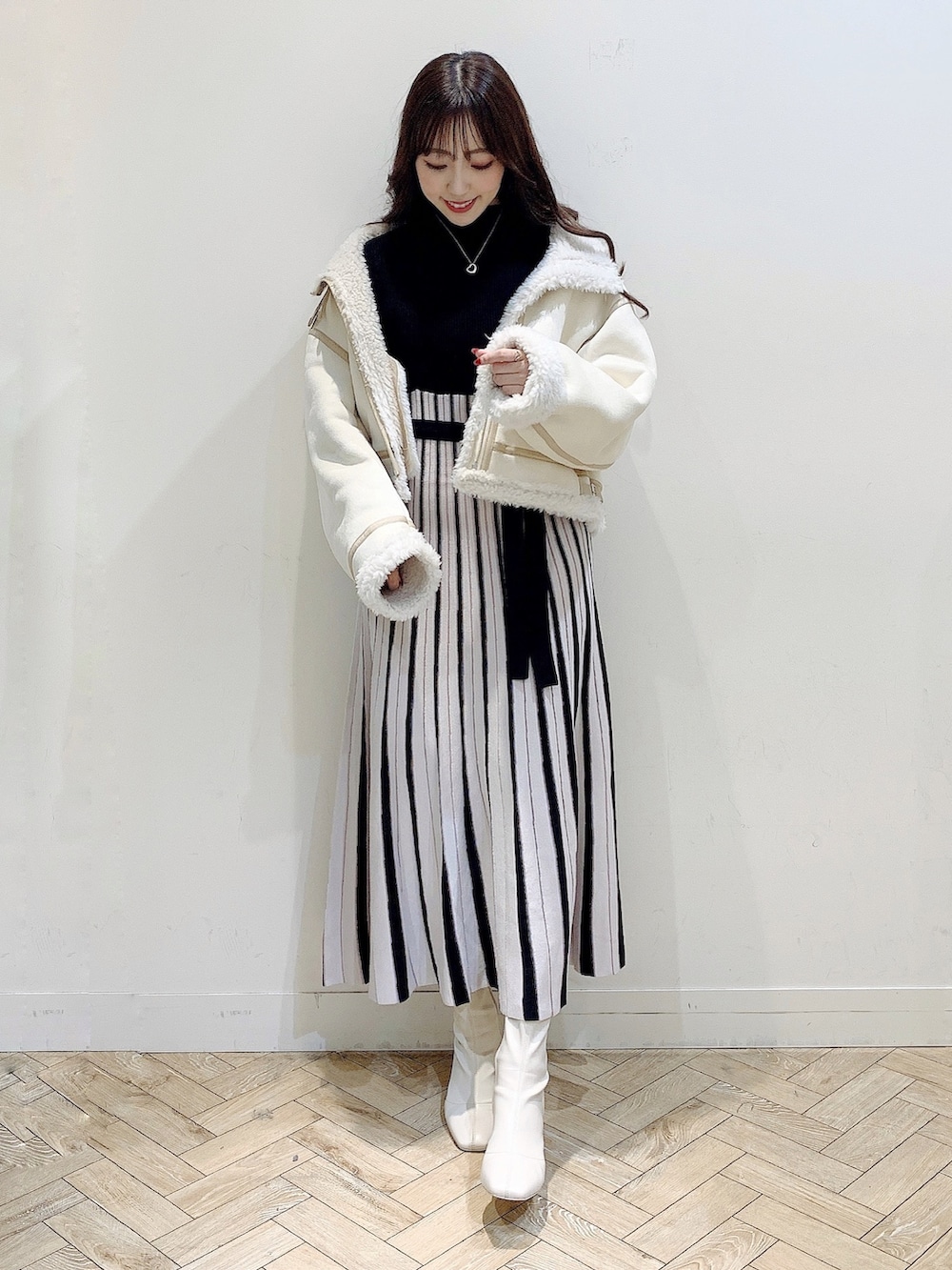 ブラック系のワンピース、ホワイト系のムートンコート、ホワイト系のブーツを着用したレディースの冬コーディネートの5枚目の写真