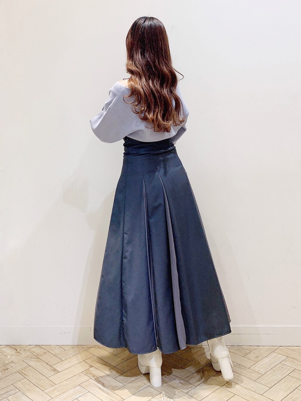 グレー系のスカート、ブルー系のニット/セーター、ホワイト系のブーツを着用したレディースの秋コーディネートの5枚目の写真