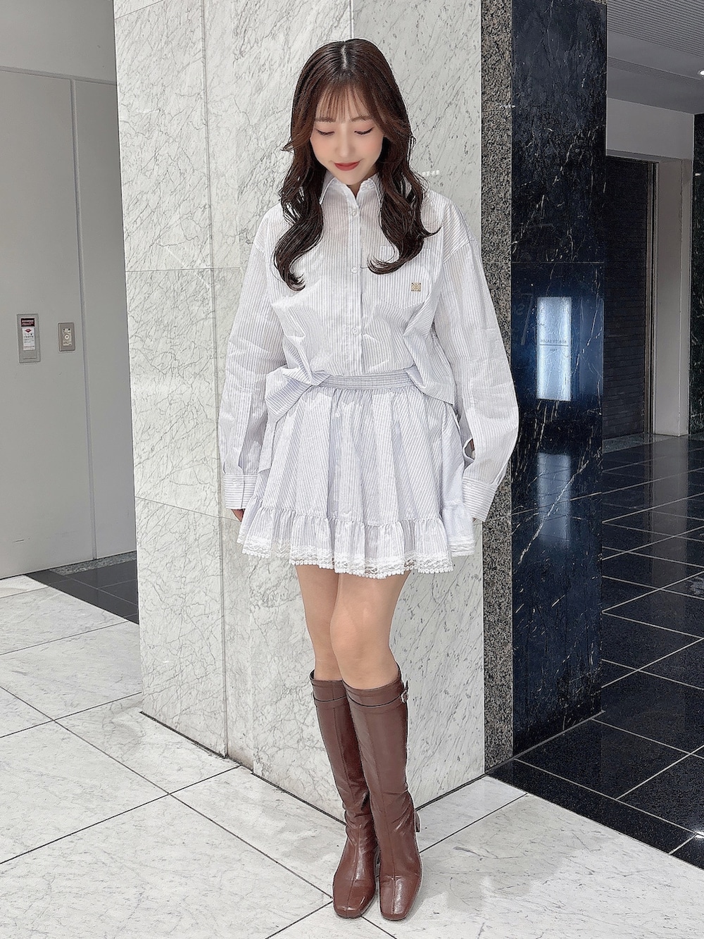 ブラウン系のブーツ、ホワイト系のシャツ/ブラウス、ホワイト系のスカートを着用したレディースの春コーディネートの2枚目の写真