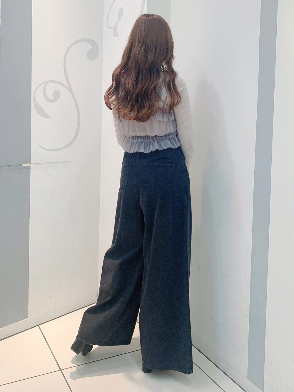 ブラック系のデニムパンツ、ブラック系のパンプス、グレー系のニット/セーターを着用したレディースの秋コーディネートの6枚目の写真