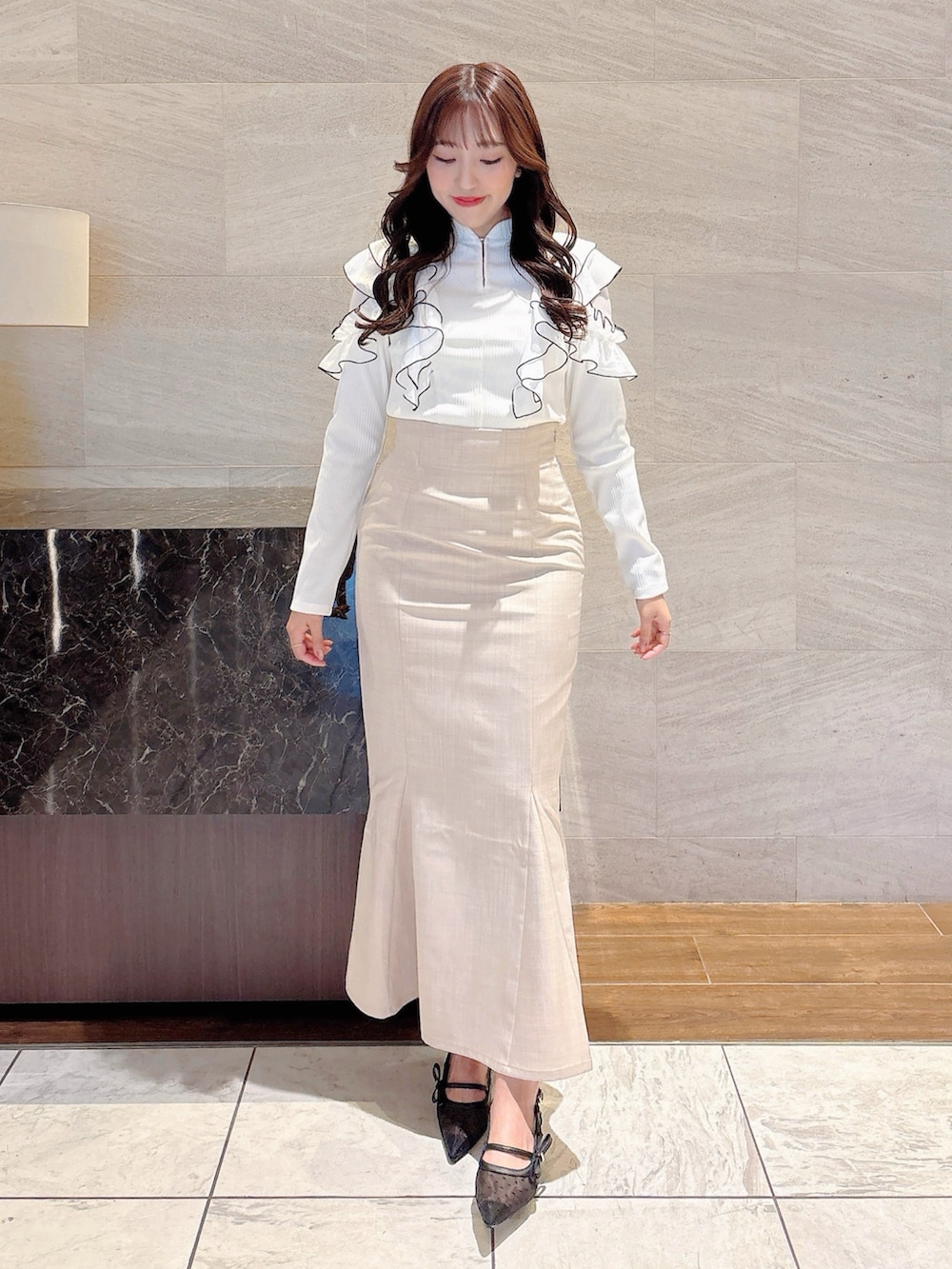 ベージュ系のスカート、ホワイト系のTシャツ/カットソー、ブラック系のパンプスを着用したレディースの春コーディネートの2枚目の写真