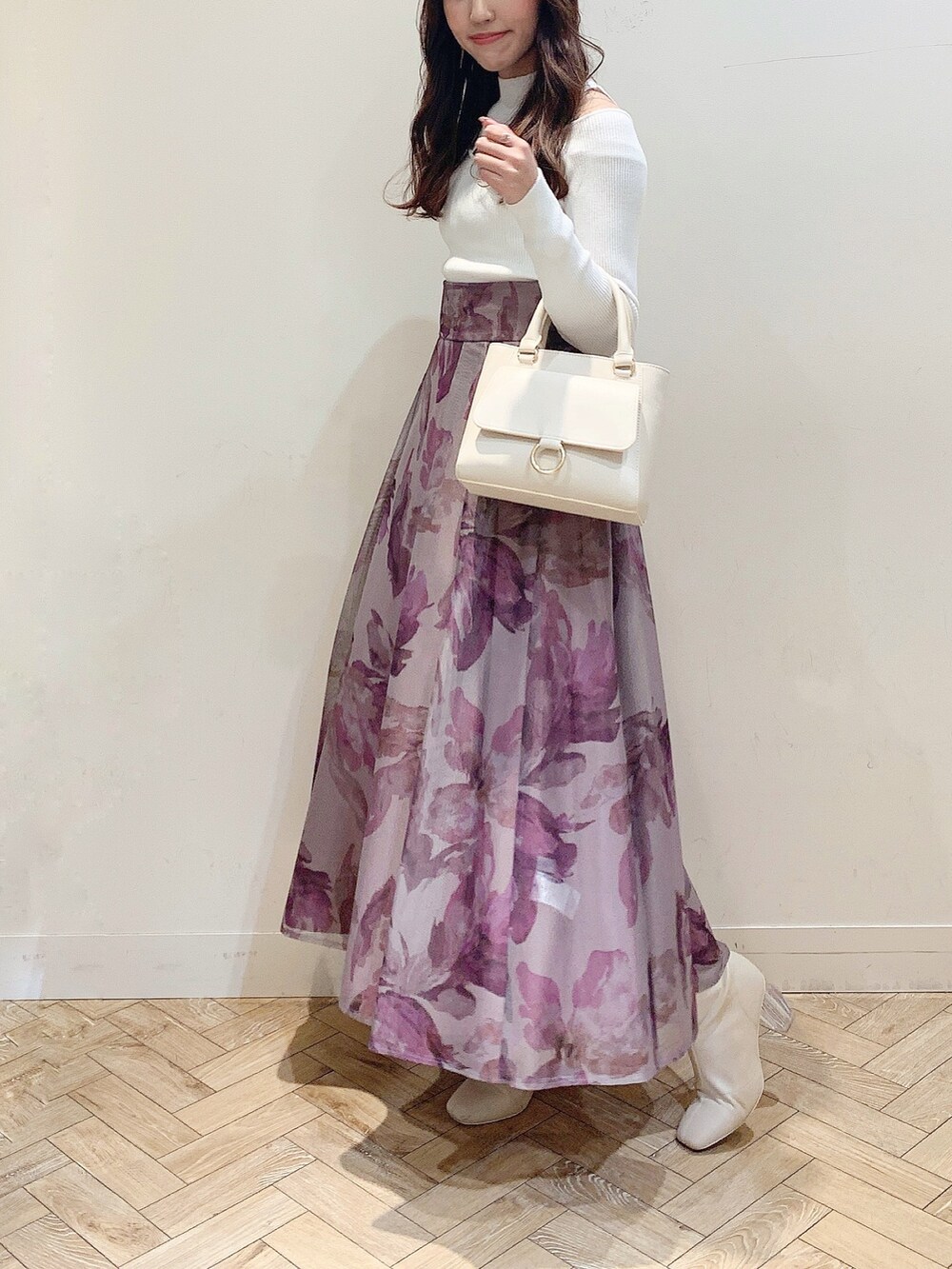 ブラウン系のスカート、ホワイト系のニット/セーター、ホワイト系のハンドバッグを着用したレディースの冬コーディネートの2枚目の写真