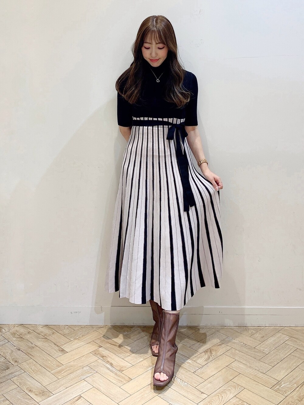 ブラック系のワンピース、ブラウン系のブーツを着用したレディースの春コーディネートの3枚目の写真