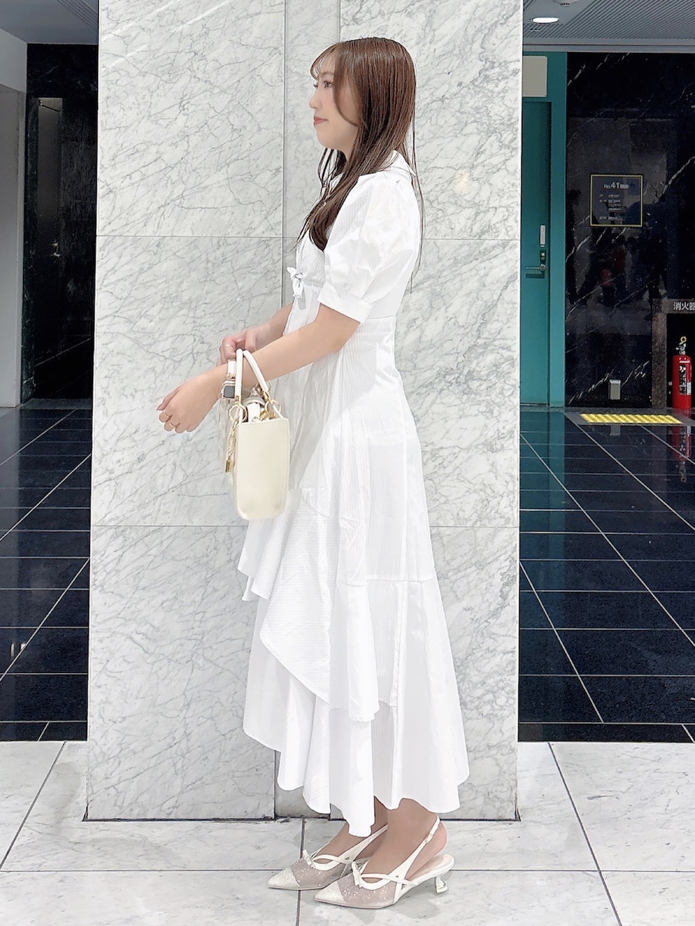 ホワイト系のワンピース、ホワイト系のパンプス、ホワイト系のハンドバッグを着用したレディースの春コーディネートの4枚目の写真