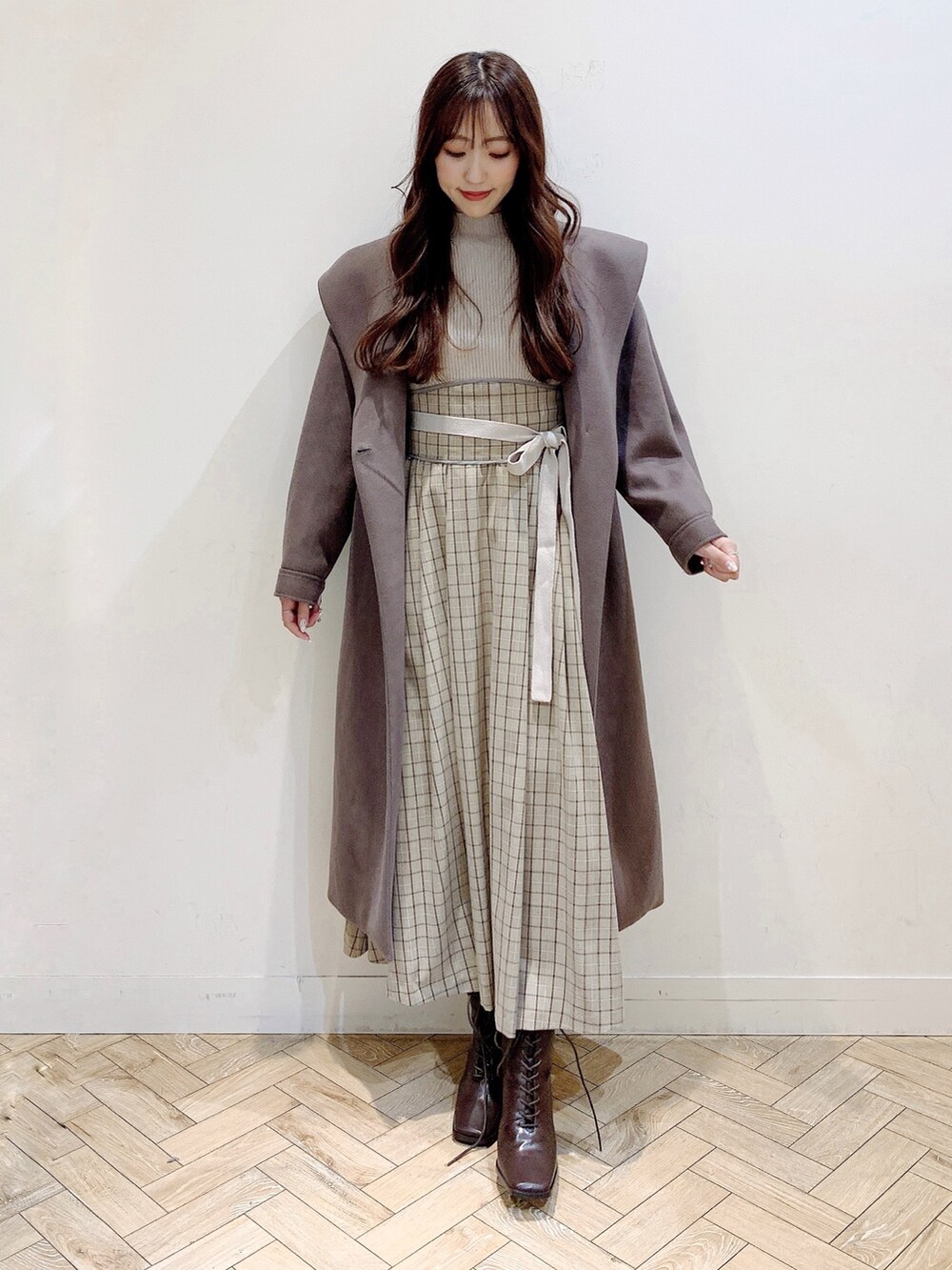 ブラウン系のチェスターコート、ブラウン系のブーツ、ベージュ系のワンピースを着用したレディースの冬コーディネートの7枚目の写真