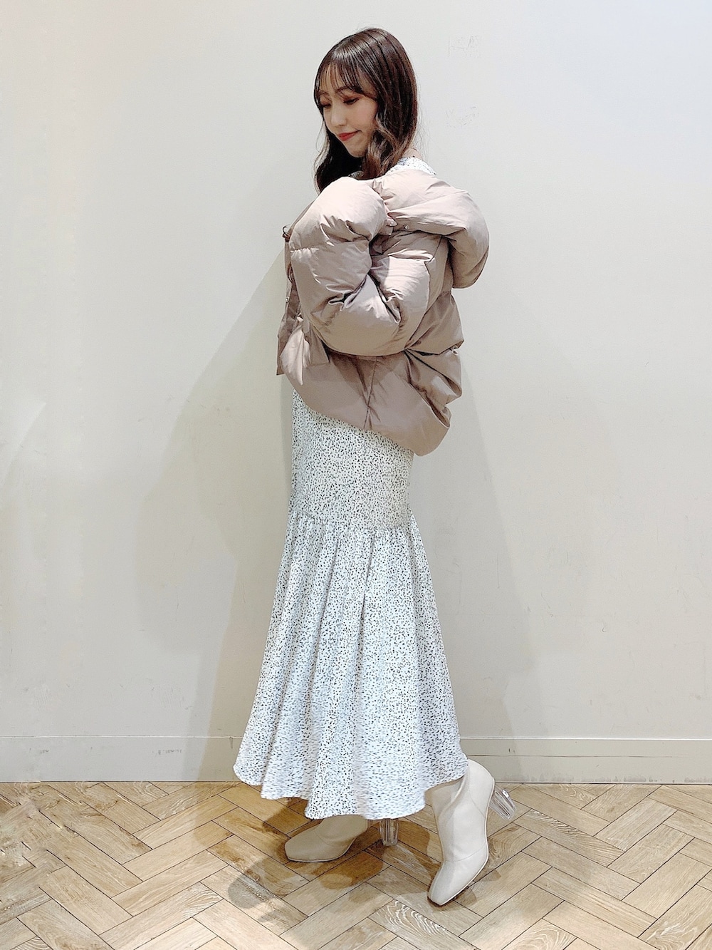 ホワイト系のワンピース、ブラウン系のダウンジャケット/コート、ホワイト系のブーツを着用したレディースの冬コーディネートの6枚目の写真