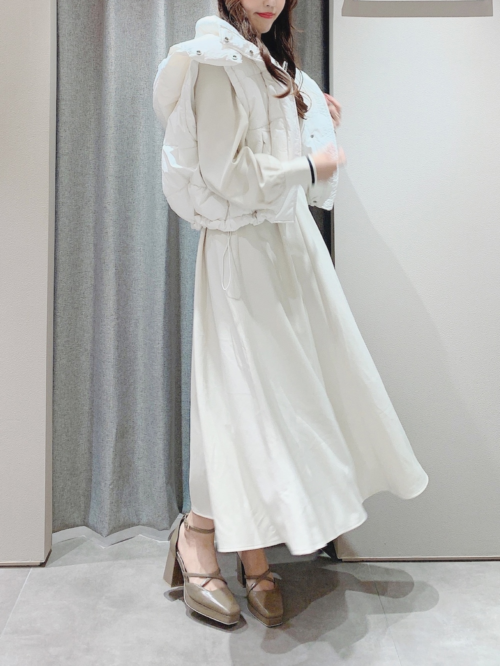 ベージュ系のパンプス、ホワイト系のワンピース、ホワイト系のダウンジャケット/コートを着用したレディースの秋コーディネートの5枚目の写真