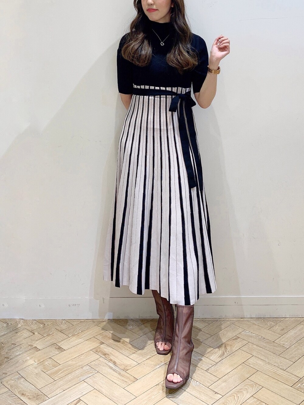 ブラック系のワンピース、ブラウン系のブーツを着用したレディースの春コーディネートの4枚目の写真