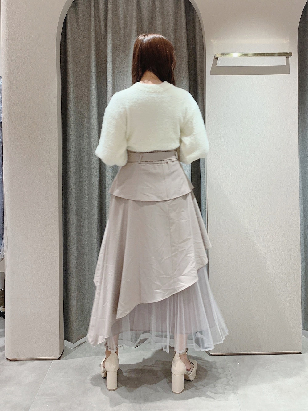ホワイト系のニット/セーター、ベージュ系のスカート、ホワイト系のパンプスを着用したレディースの秋コーディネートの6枚目の写真