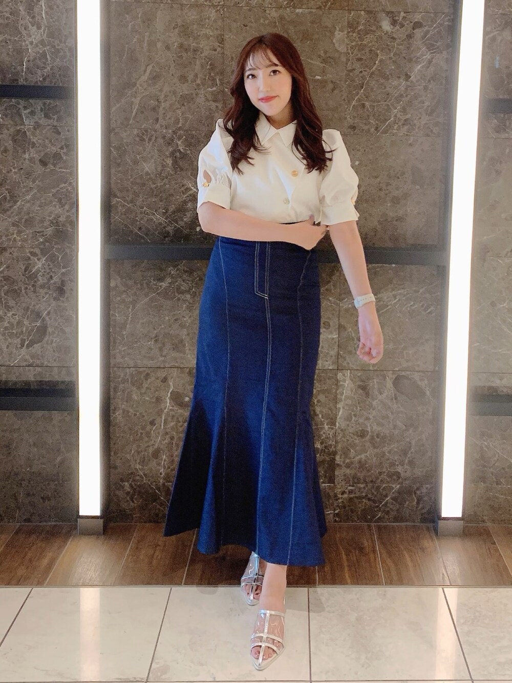 シルバー系のパンプス、ブルー系のスカート、ホワイト系のシャツ/ブラウスを着用したレディースの夏コーディネートの2枚目の写真