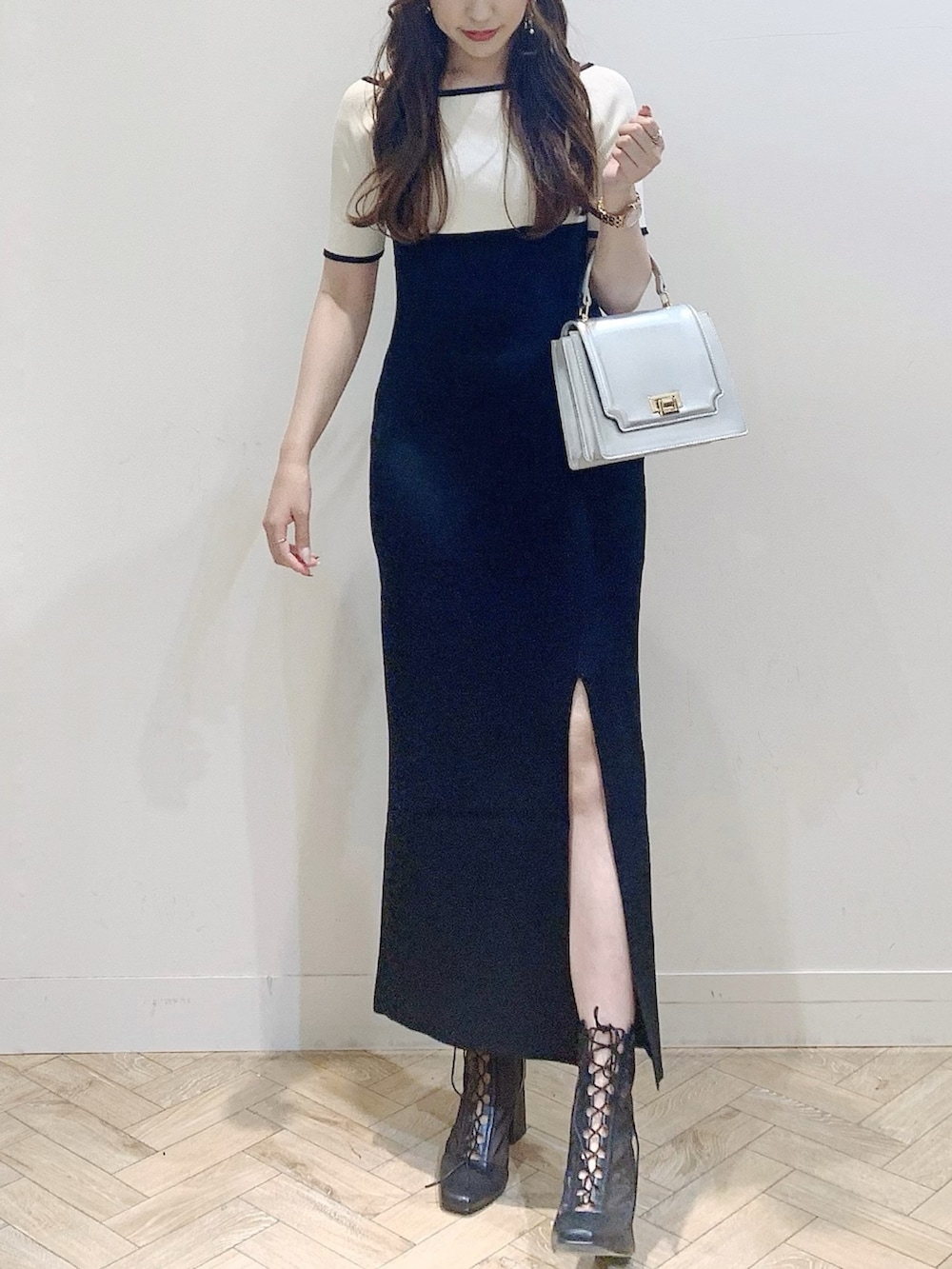 ブラック系のワンピース、シルバー系のハンドバッグ、ブラック系のブーツを着用したレディースの夏コーディネートの2枚目の写真