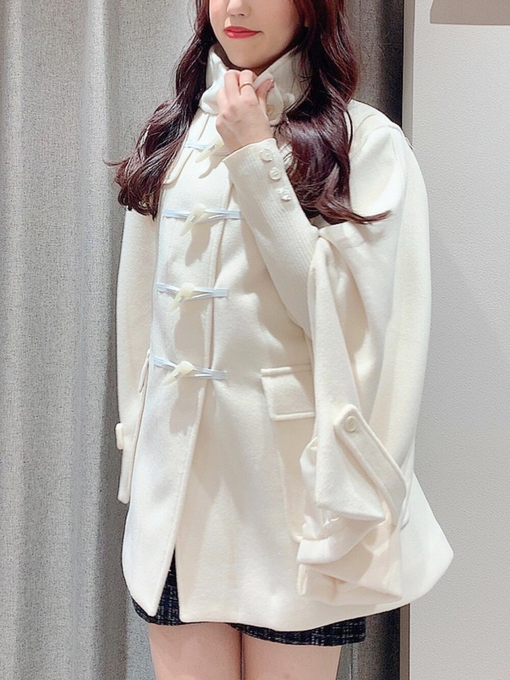 ホワイト系のダッフルコート、ホワイト系のニット/セーター、ブラック系のスカートを着用したレディースの秋コーディネートの8枚目の写真