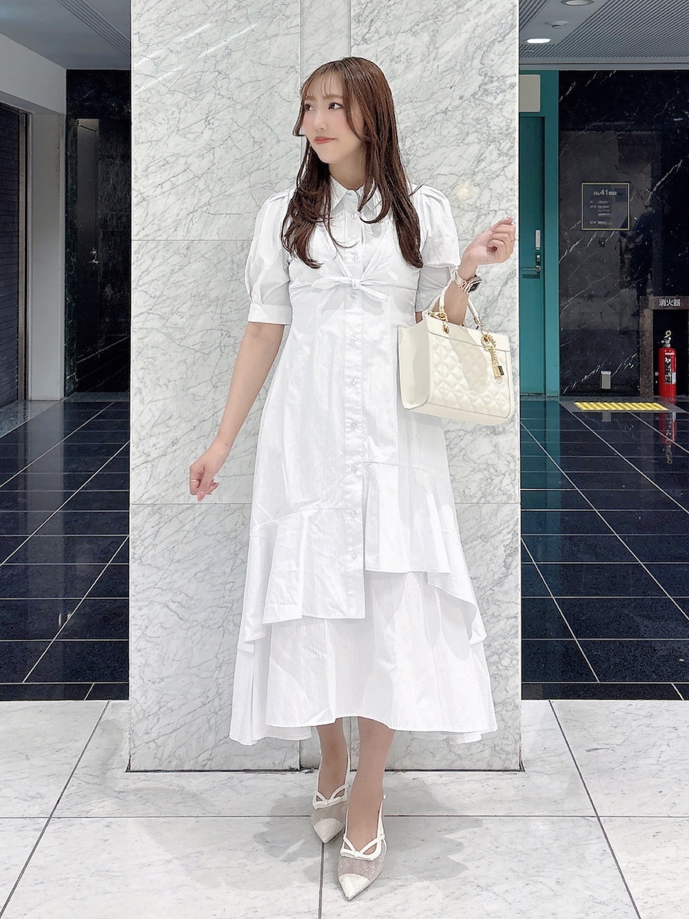 ホワイト系のワンピース、ホワイト系のパンプス、ホワイト系のハンドバッグを着用したレディースの春コーディネートの3枚目の写真