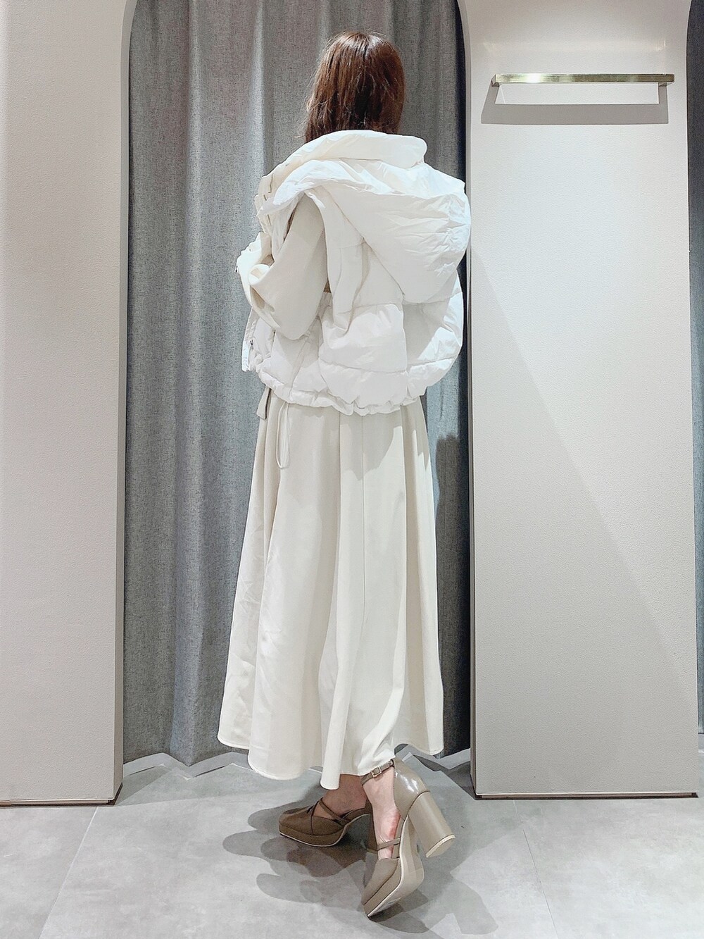 ベージュ系のパンプス、ホワイト系のワンピース、ホワイト系のダウンジャケット/コートを着用したレディースの秋コーディネートの6枚目の写真