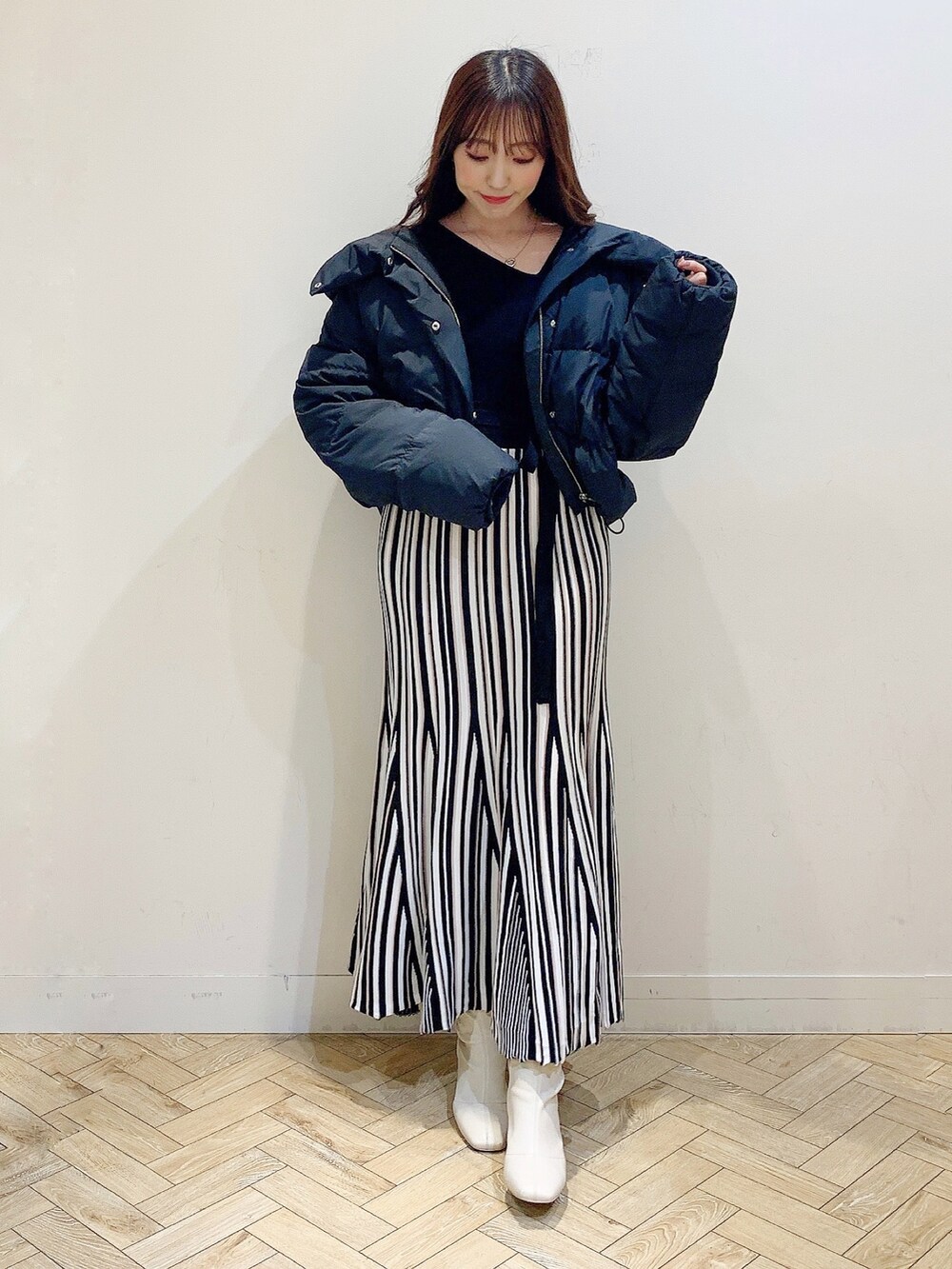 ブラック系のワンピース、ブラック系のダウンジャケット/コート、ホワイト系のブーツを着用したレディースの冬コーディネートの6枚目の写真