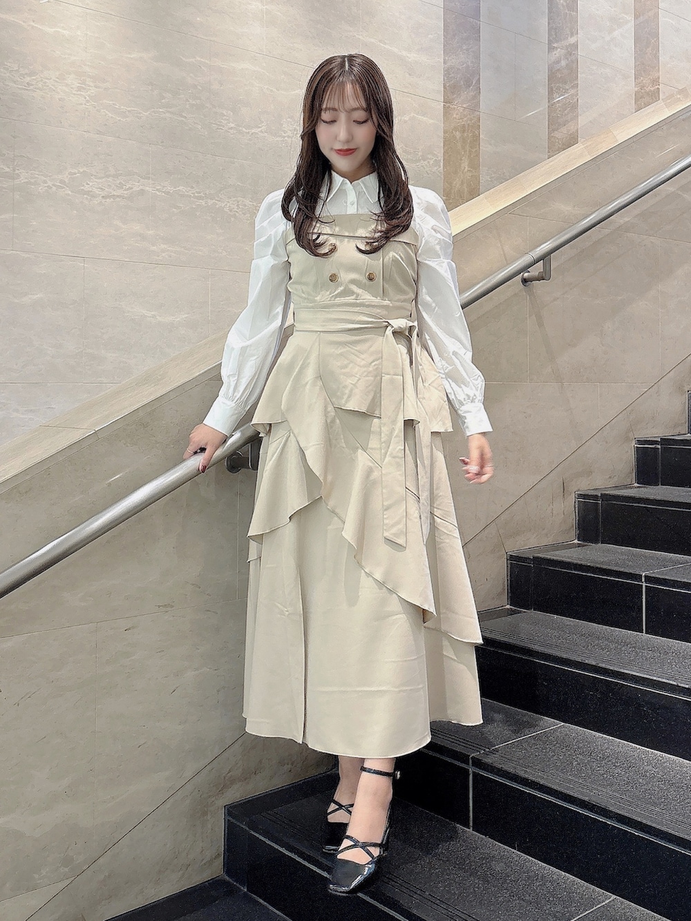 ベージュ系のワンピース、ブラック系のサンダルを着用したレディースの冬コーディネートの2枚目の写真