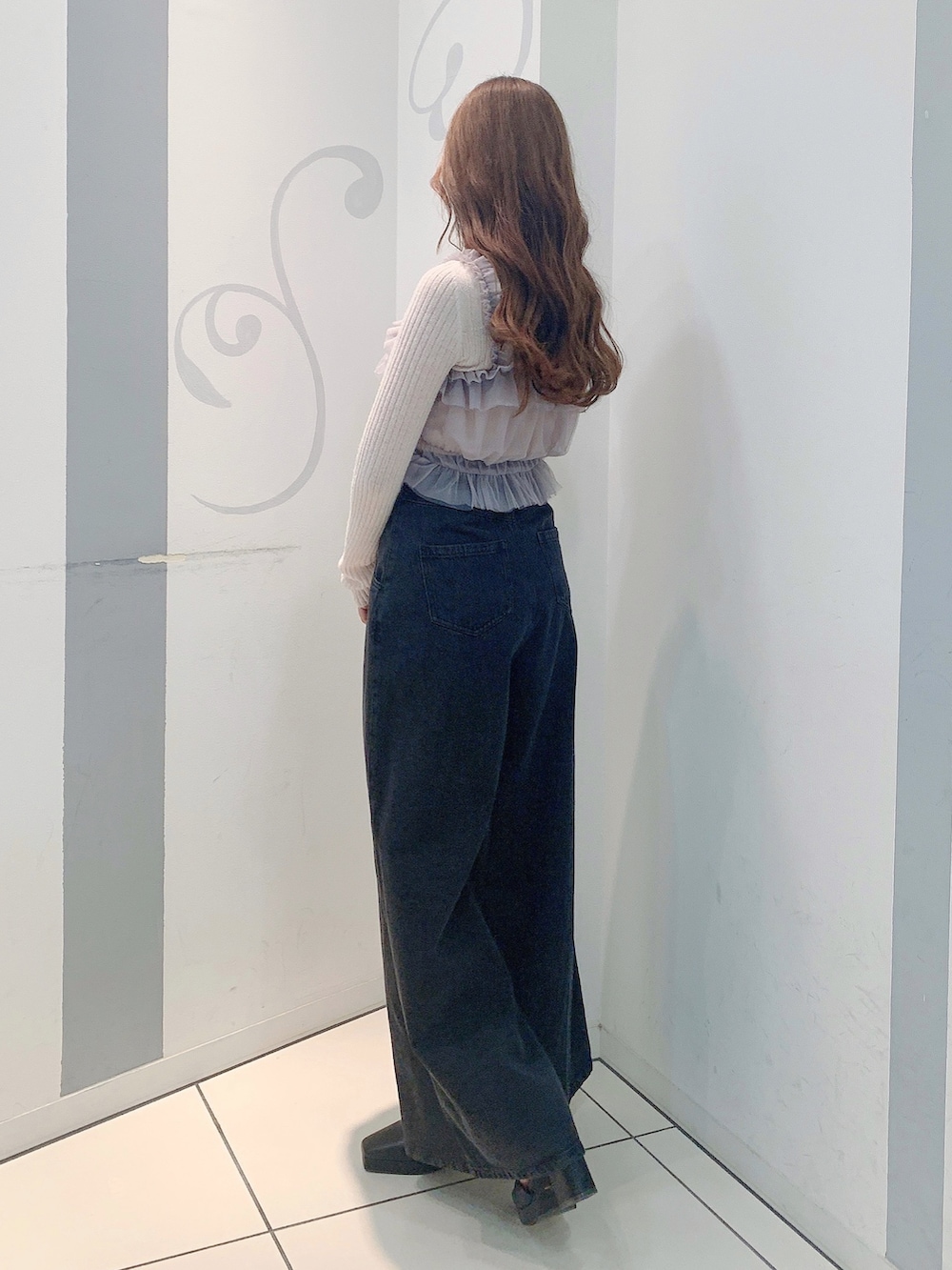 ブラック系のデニムパンツ、ブラック系のパンプス、グレー系のニット/セーターを着用したレディースの秋コーディネートの4枚目の写真