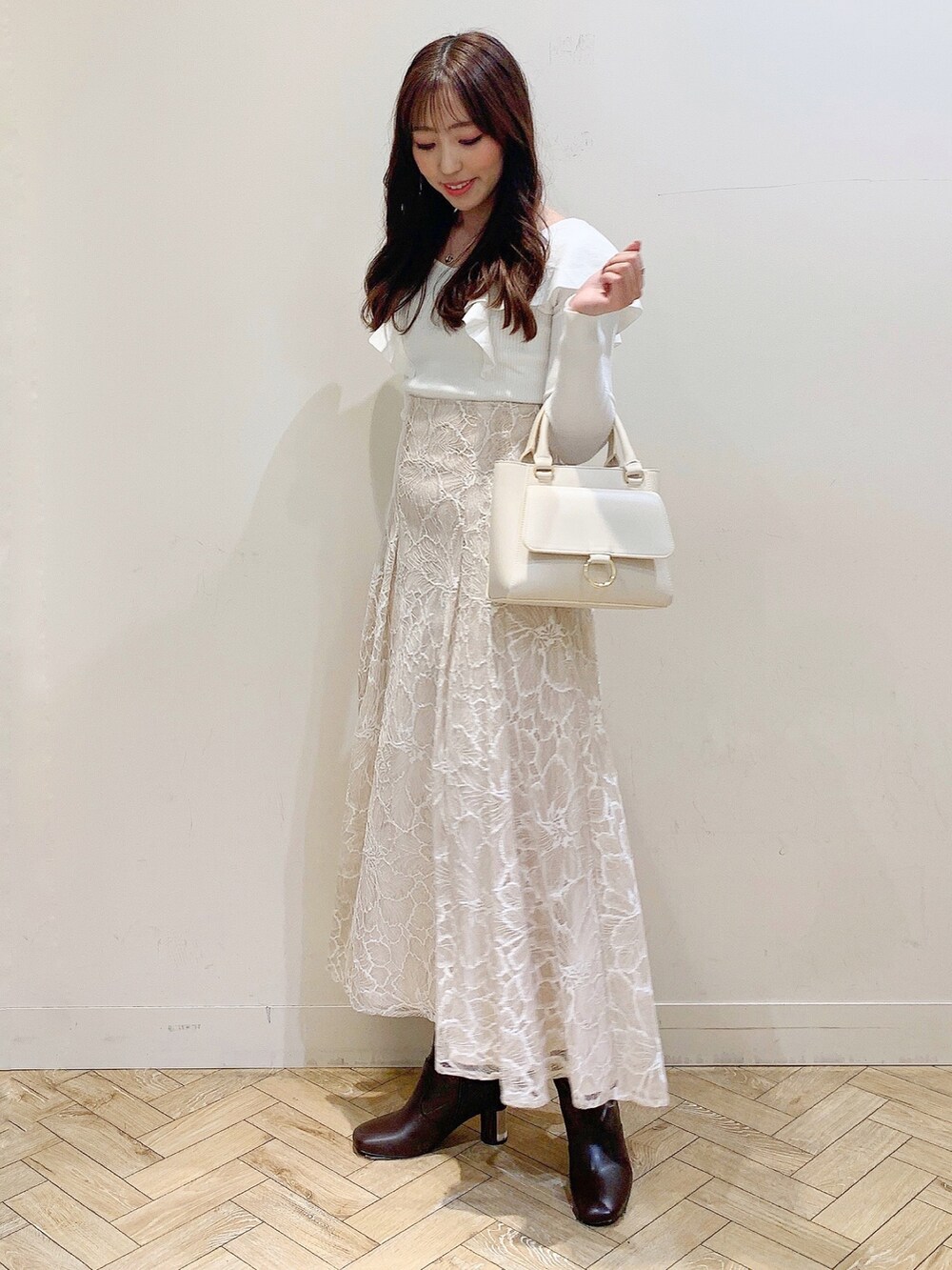 ベージュ系のスカート、ブラウン系のブーツ、ホワイト系のニット/セーターを着用したレディースの冬コーディネートの2枚目の写真