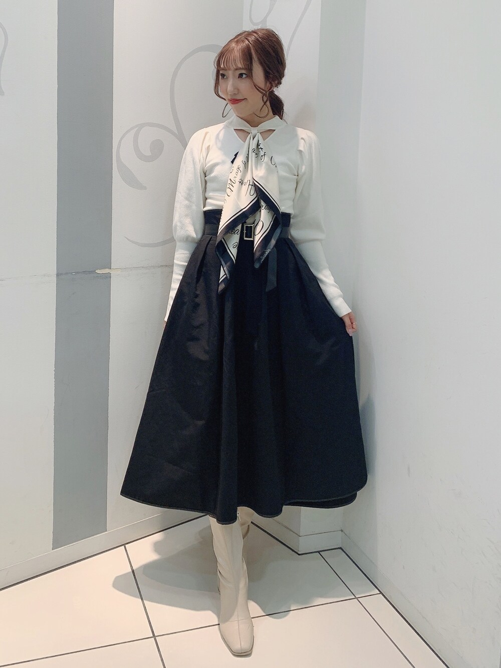 ホワイト系のブーツ、ブラック系のスカート、ホワイト系のニット/セーターを着用したレディースの秋コーディネートの2枚目の写真