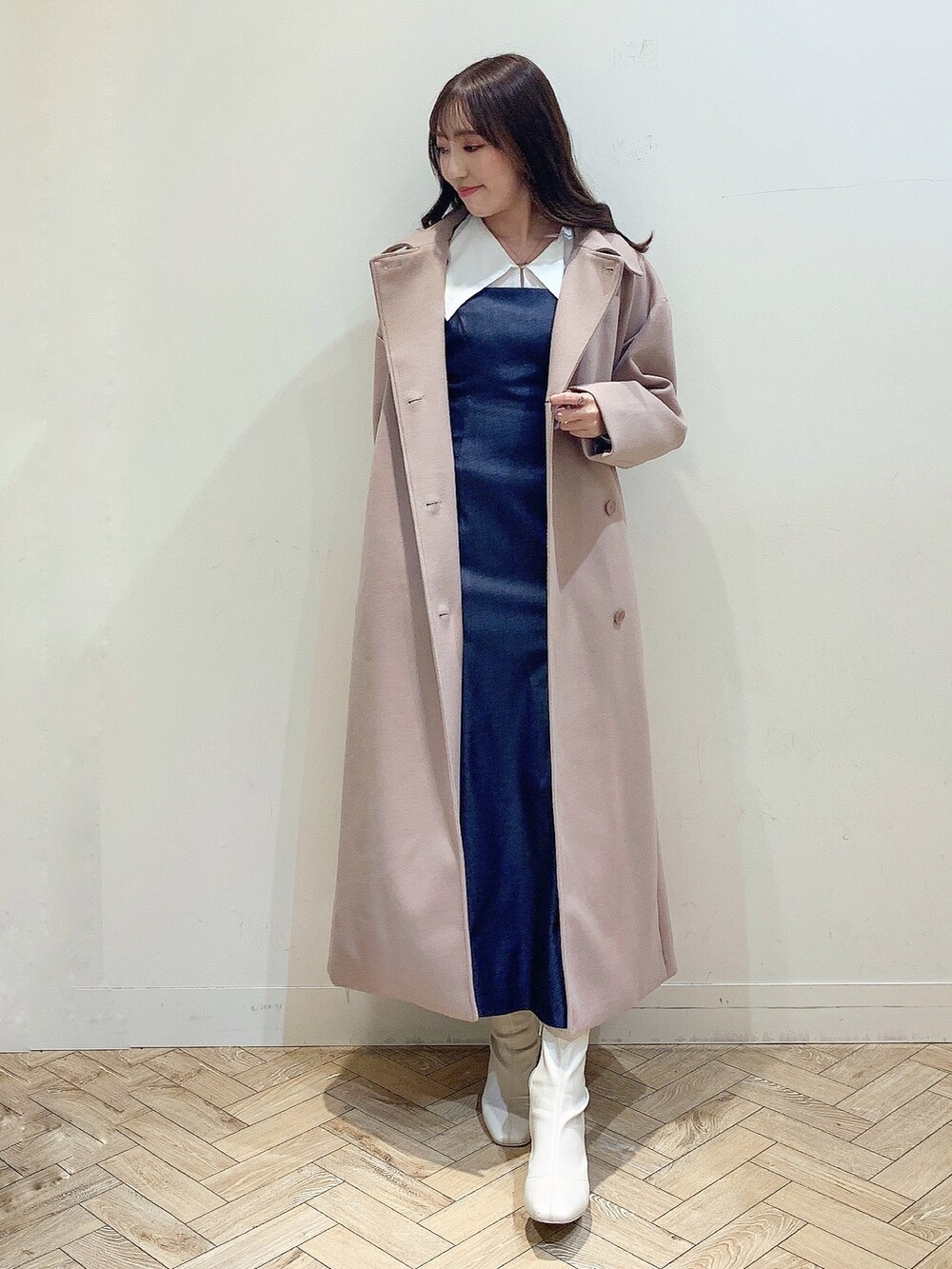 ブルー系のワンピース、ホワイト系のブーツ、ベージュ系のステンカラーコートを着用したレディースの冬コーディネートの5枚目の写真