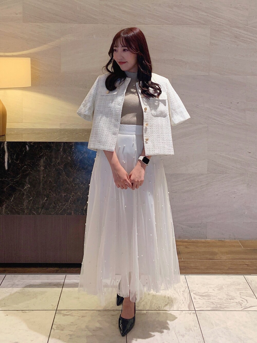 ホワイト系のスカート、ホワイト系のノーカラージャケット、ベージュ系のニット/セーターを着用したレディースの夏コーディネートの2枚目の写真
