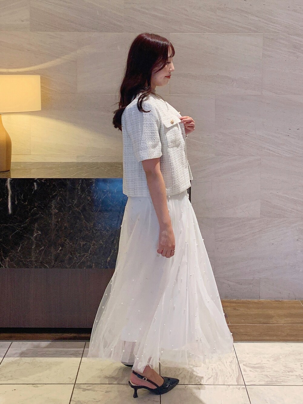 ホワイト系のスカート、ホワイト系のノーカラージャケット、ベージュ系のニット/セーターを着用したレディースの夏コーディネートの7枚目の写真