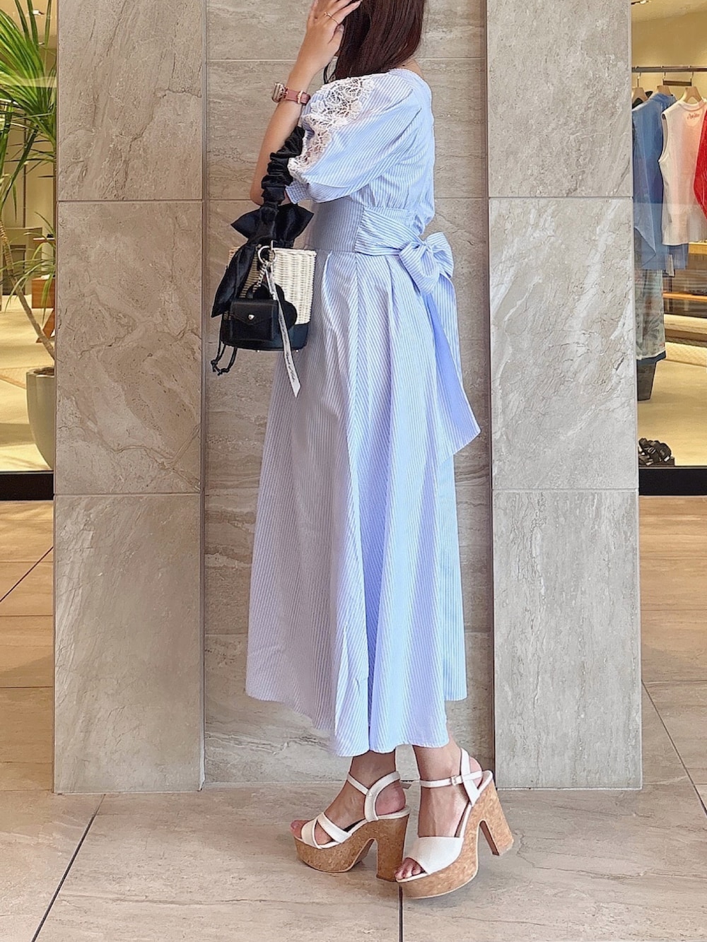 ブラック系のかごバッグ、ホワイト系のサンダル、ブルー系のワンピースを着用したレディースの夏コーディネートの3枚目の写真