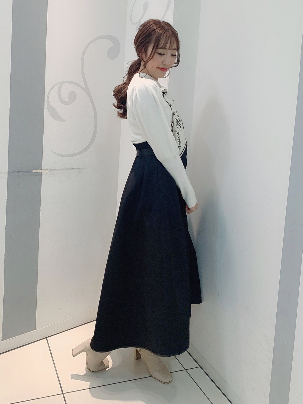 ホワイト系のブーツ、ブラック系のスカート、ホワイト系のニット/セーターを着用したレディースの秋コーディネートの3枚目の写真