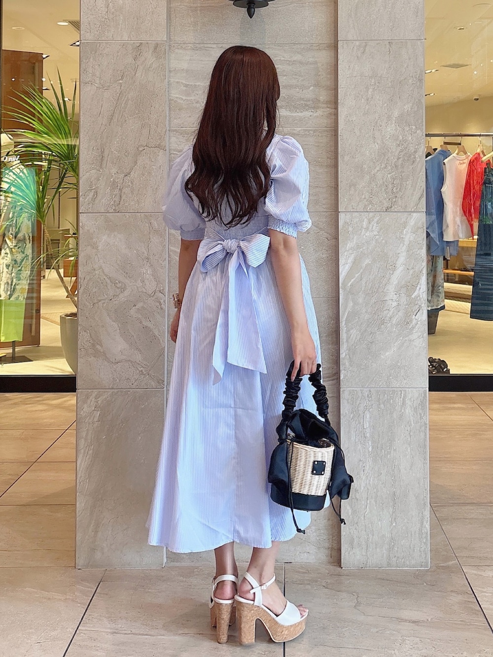 ブラック系のかごバッグ、ホワイト系のサンダル、ブルー系のワンピースを着用したレディースの夏コーディネートの6枚目の写真