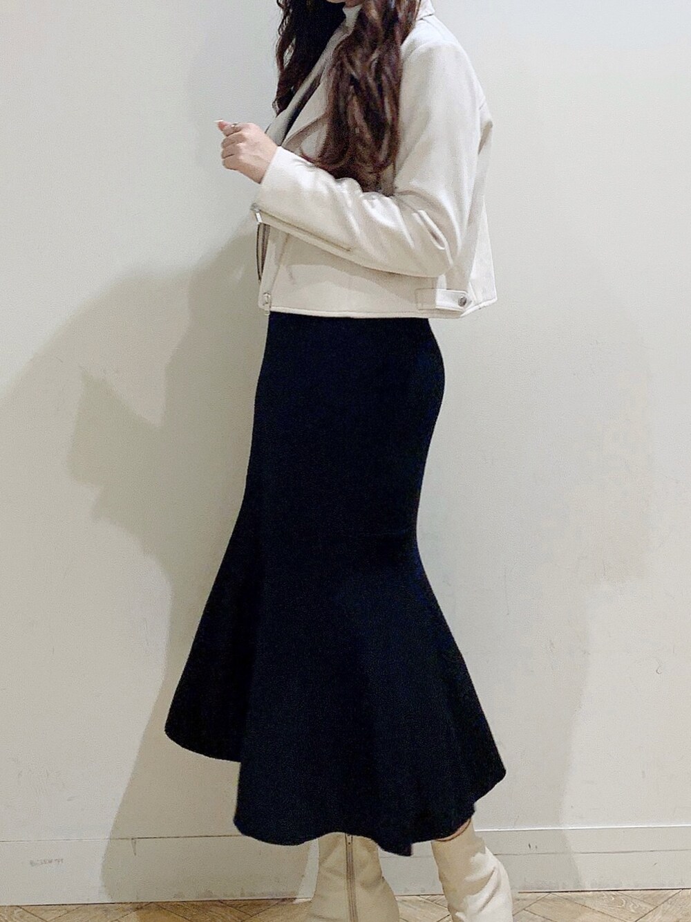 ブラック系のワンピース、ホワイト系のブーツ、ベージュ系のライダースジャケットを着用したレディースの冬コーディネートの6枚目の写真