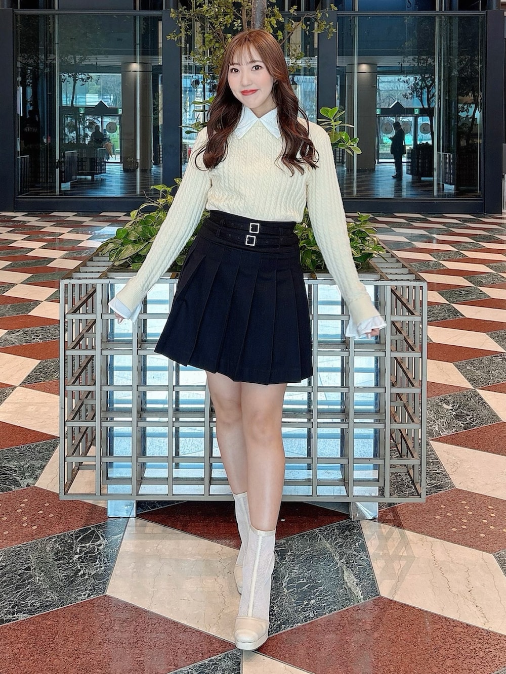 ホワイト系のブーツ、ブラック系のスカート、ホワイト系のニット/セーターを着用したレディースの冬コーディネートの2枚目の写真