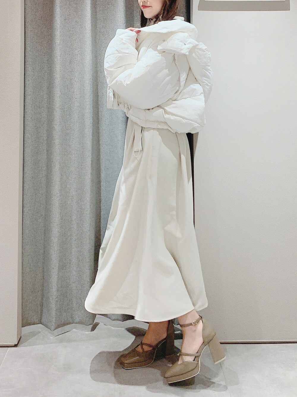 ベージュ系のパンプス、ホワイト系のワンピース、ホワイト系のダウンジャケット/コートを着用したレディースの秋コーディネートの2枚目の写真