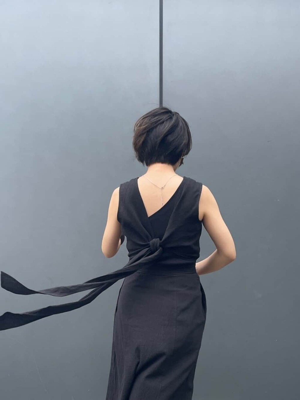 オレンジ系のかごバッグ、ブラック系のサンダル、ブラック系のタンクトップを着用したレディースの春コーディネートの4枚目の写真