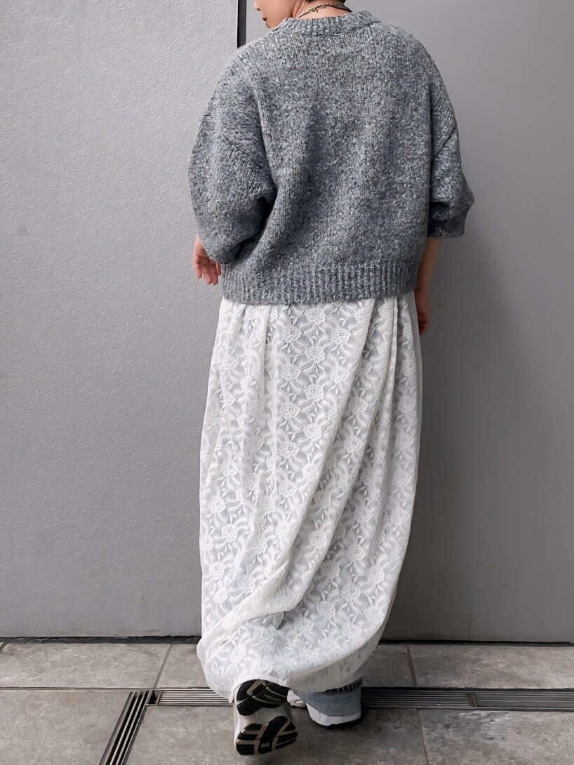 グレー系のニット/セーター、ホワイト系のワンピース、ブルー系のデニムパンツを着用したレディースの秋コーディネートの4枚目の写真