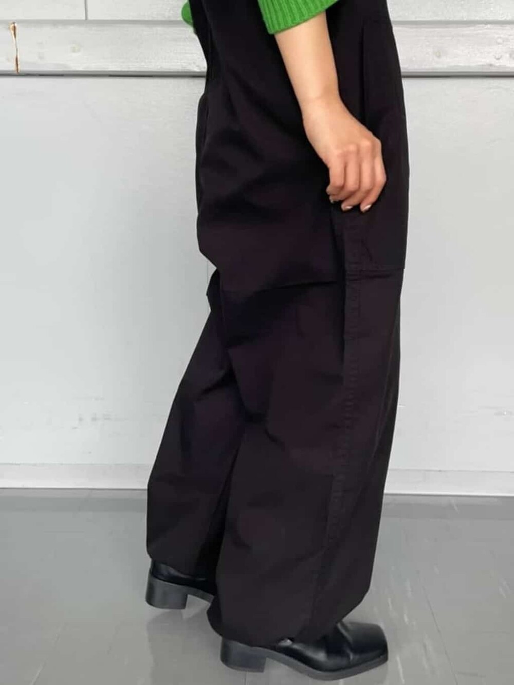 ブラック系のつなぎ/オールインワン、グリーン系のニット/セーター、ブラック系のブーツを着用したレディースの秋コーディネートの3枚目の写真