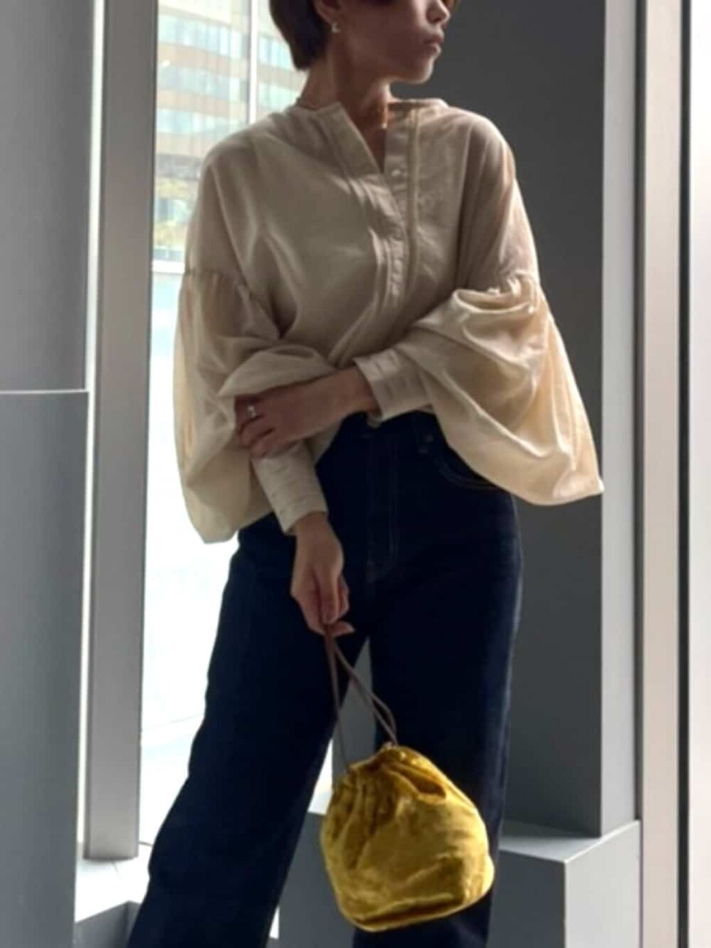 イエロー系のハンドバッグ、ブルー系のデニムパンツ、ホワイト系のシャツ/ブラウスを着用したレディースの夏コーディネートの2枚目の写真