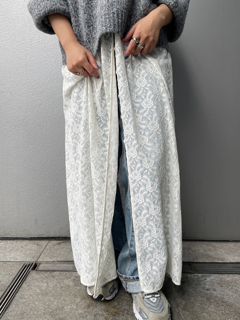 グレー系のニット/セーター、ホワイト系のワンピース、ブルー系のデニムパンツを着用したレディースの秋コーディネートの5枚目の写真