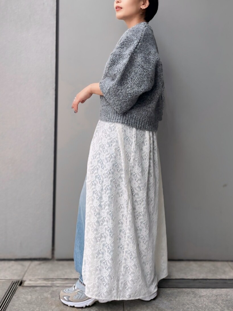 グレー系のニット/セーター、ホワイト系のワンピース、ブルー系のデニムパンツを着用したレディースの秋コーディネートの3枚目の写真