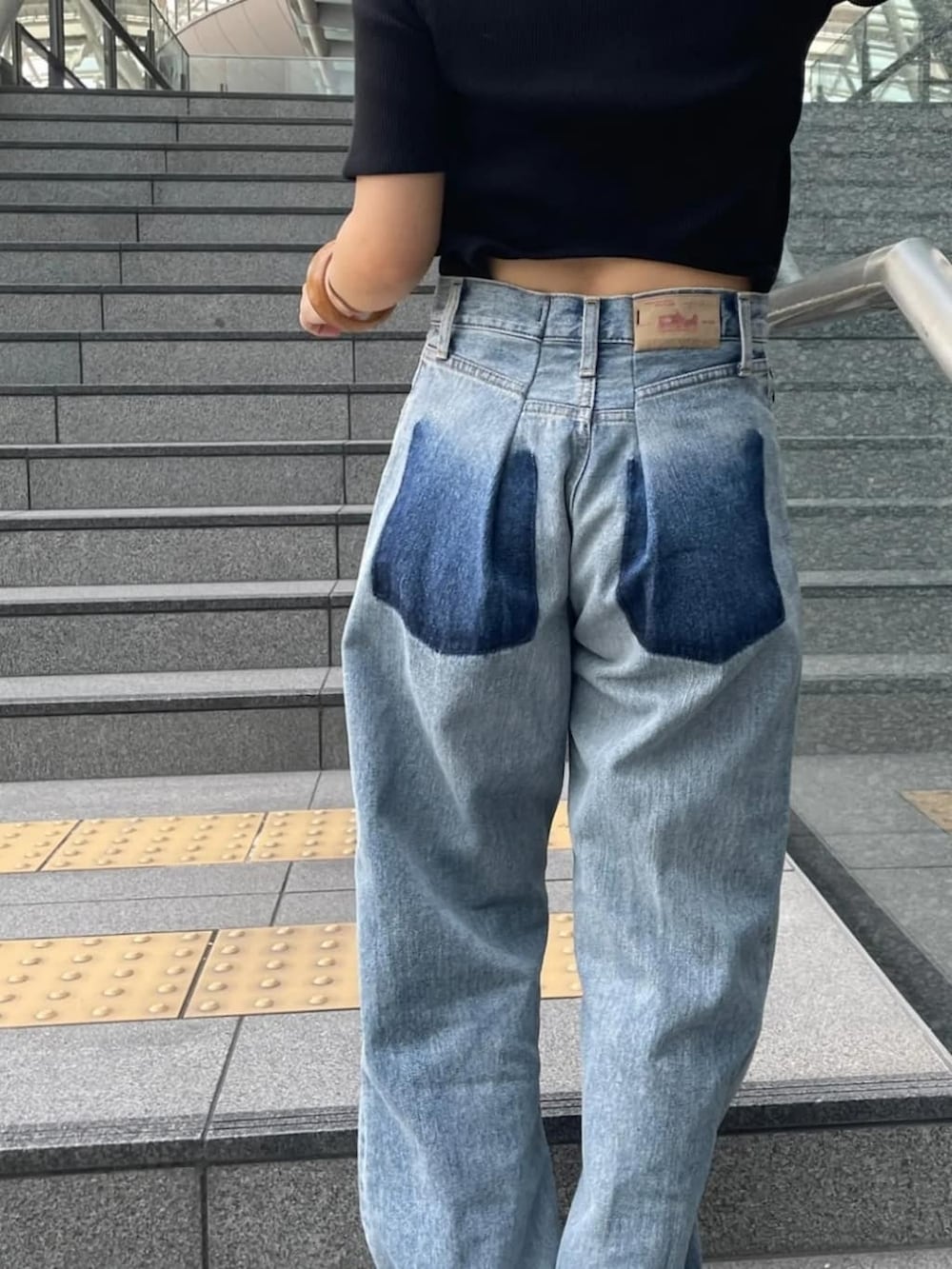 ブルー系のデニムパンツ、ブラック系のTシャツ/カットソー、ブラック系のサンダルを着用したレディースの夏コーディネートの2枚目の写真