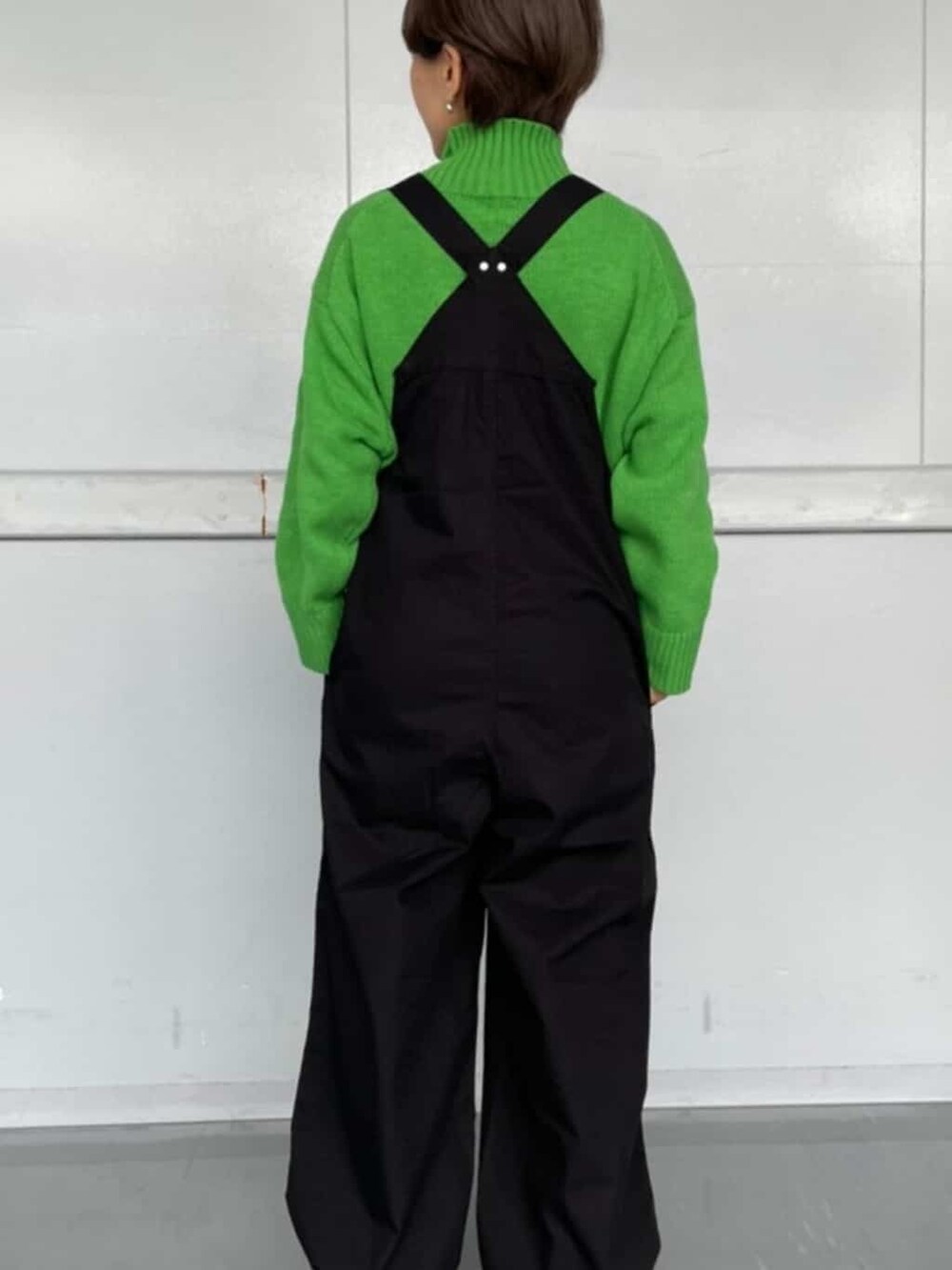ブラック系のつなぎ/オールインワン、グリーン系のニット/セーター、ブラック系のブーツを着用したレディースの秋コーディネートの4枚目の写真