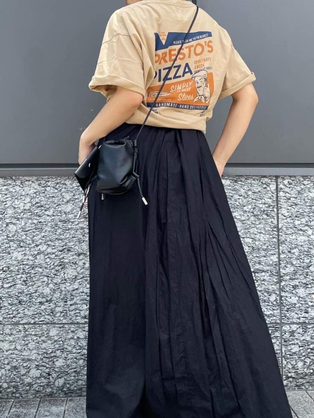 ブラック系のワンピース、ベージュ系のTシャツ/カットソーを着用したレディースの夏コーディネートの2枚目の写真